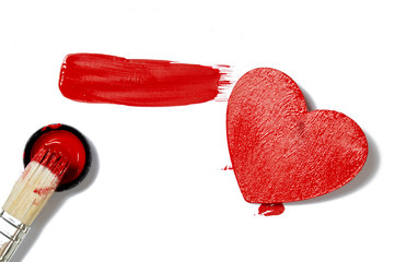 red heart on white and horizontal smear of red paint and brush on white background