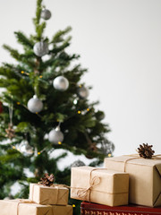 Christmas gifts in craft packaging on a wooden table against the background of a decorated Christmas tree. The concept of Christmas and New Year.