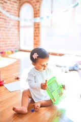 Beautiful infant happy at kindergarten around colorful toys drawing on magnetic blackboard