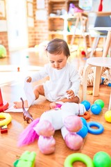 Beautiful infant happy at kindergarten around colorful toys
