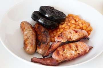 Cumberland sausages, bacon, baked beans and black pudding in a white bowl