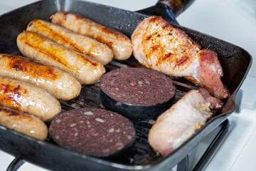 Sausages, bacon and black pudding cooking in a griddle pan