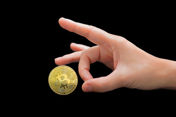 Plakat Female fingers throw out bitcoin. Disapproval sign. Close-up golden virtual currency bitcoin isolated on black background. Physical Bitcoin. Crypto currency concept. 