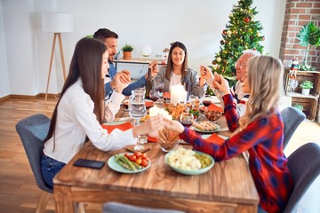 Beautiful family meeting smiling happy and confident. Praying taking hands before eating roasted turkey celebrating Christmas at home