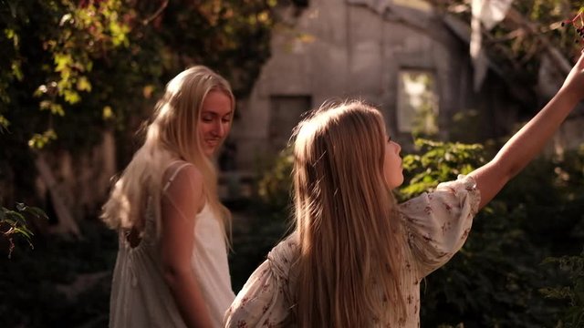 Happy mother and daughter enjoying nature in the old abandoned green house during summer day. Dreamy fairytail vibe.