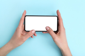 Smartphone in female hands on blue background