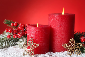 Christmas candles with decorative stars and fir tree branches on red background