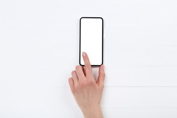 Smartphone with female hand on white wooden table