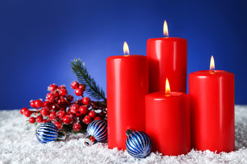 Christmas candles with baubles and red berries on blue background