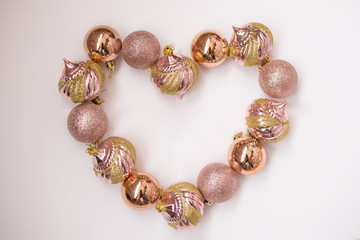 the figure of the heart of Christmas balls rose gold on a light background