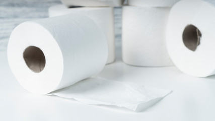 A pile of toilet paper rolls on a white table on a background of blue wall texture. Hygiene products