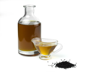 A handful of black cumin seeds and black seed oil in a glass bottle and gravy boat. Isolated on white background.