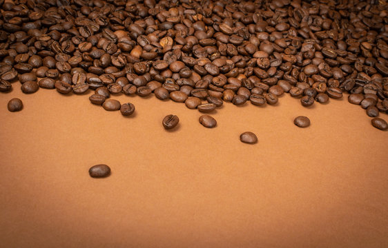 Dark brown whole coffee beans on wood background with copyspace