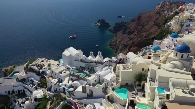 Aerial drone video of famous whitewashed and colourful at the same time picturesque village of Oia built on a cliff, Santorini island, Cyclades, Greece