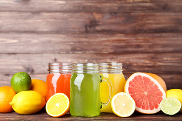 Citrus juice in glass jars with fruits on wooden table