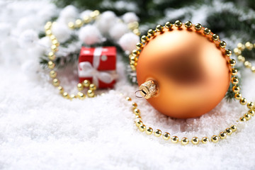 Christmas bauble with fir tree branches and gift box on white snow