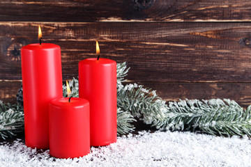 Christmas candles with fir tree branches on brown wooden background