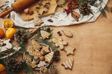 Christmas gingerbread cookies on vintage plate and anise, cinnamon, pine cones and cedar branches, rolling pin on rustic table, flat lay with space for text