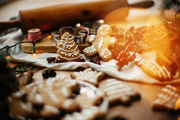 Festive gingerbread cookies with anise, cinnamon, pine cones, cedar branches and golden lights bokeh on rustic table. Atmospheric image. Merry Christmas