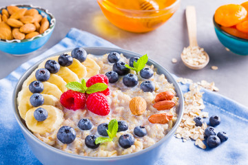 Healthy homemade oatmeal with berries and nuts for breakfast. Oatmeal with fruits, nuts and honey. Oatmeal with blueberries, banana and raspberries