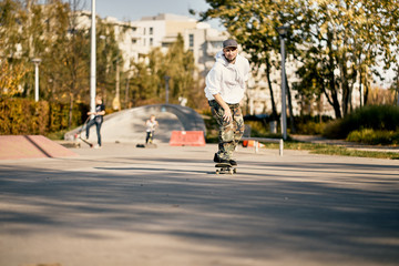 Man in skatepark rides skateboard on warm autumn day