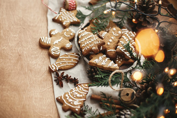 Merry Christmas. Festive gingerbread cookies with anise, cinnamon, pine cones, cedar branches and golden lights bokeh on rustic table. Space for text. Seasons greetings