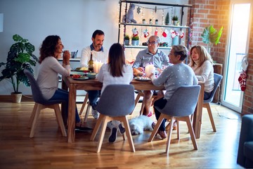 Family and friends dining at home celebrating christmas eve with traditional food and decoration, all sitting on the table together