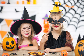 Young girls in halloween costumes sitting by the table