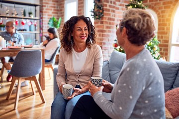 Family and friends dining at home celebrating christmas eve with traditional food and decoration, women talking together happy and casual