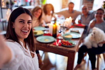 Family and friends dining at home celebrating christmas eve with traditional food and decoration, taking a selfie picture together