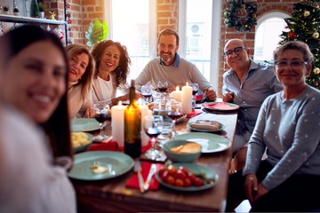Family and friends dining at home celebrating christmas eve with traditional food and decoration, taking a selfie picture together