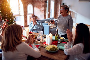 Family and friends dining at home celebrating christmas eve with traditional food and decoration, making a toast for new year best wishes