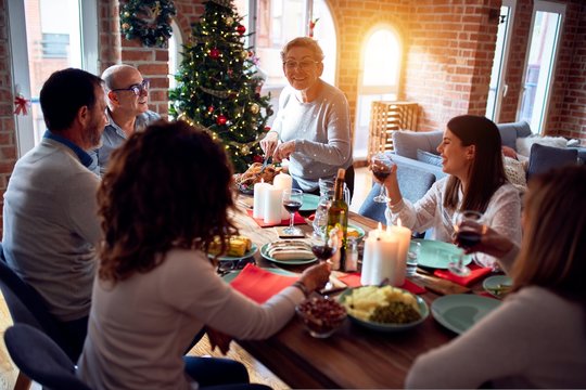 Family and friends dining at home celebrating christmas eve with traditional food and decoration, preparing turkey for dinner