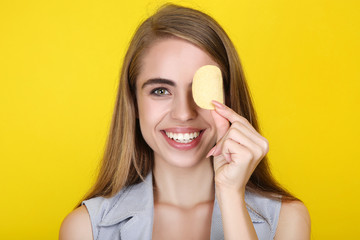 Young beautiful girl with potato chip on yellow background