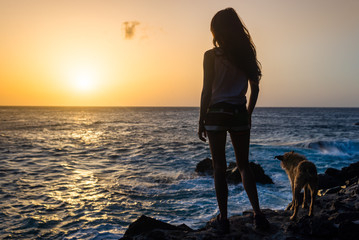 girl with her dog at sunset on the sea