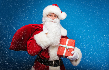 Christmas and New year concepts. Happy beautiful Santa Claus in red costume is posing over blue winter background.