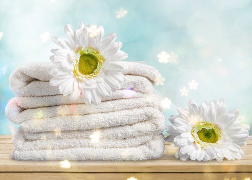 Pile of  fluffy towels with flowers on background