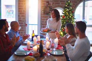 Beautiful family smiling happy and confident. Showing roasted turkey and applauding celebrating Christmas at home