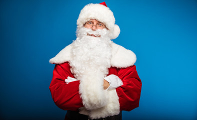 Get ready for miracles. Authentic Santa Claus is posing with his arms folded and looks right at the camera.