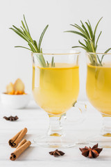 Sea buckthorn drink with honey, ginger, cinnamon and star anise on a white wood background.