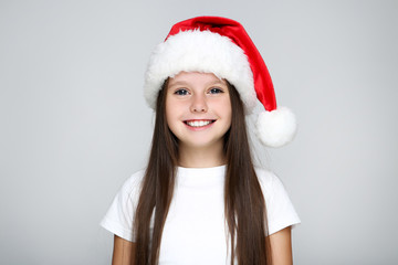 Little girl in christmas hat on grey background
