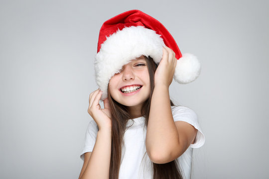 Little girl in christmas hat on grey background