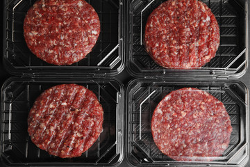Plastic containers with raw meat cutlets for burger, top view