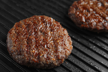Prepared meat cutlets for burger on grill, closeup