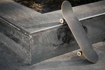 Foto op Plexiglas View of black skateboard in concrete skatepark on warm day © superelaks