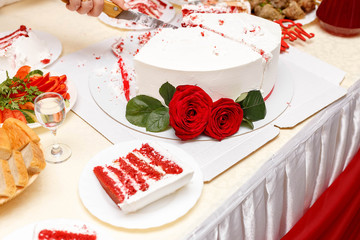 cutting wedding cake decorated with roses