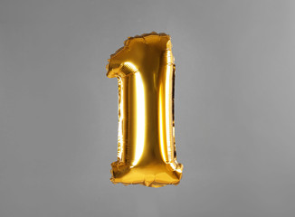 Golden number one balloon on grey background