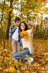 Fototapeta premium mom and son take selfies in the autumn forest. copy space