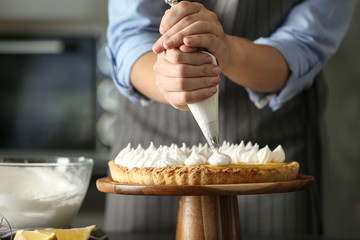 Woman preparing lemon meringue pie in kitchen, closeup