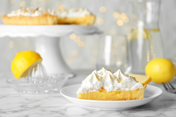 Plate with piece of delicious lemon meringue pie on white marble table